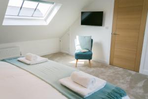 1 dormitorio con 1 cama y 1 silla azul en Bwncath & Hebog, en Llanrhwydrys