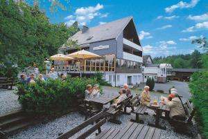 un gruppo di persone seduti ad un tavolo da picnic di fronte a un edificio di Ginsberger Heide a Hilchenbach