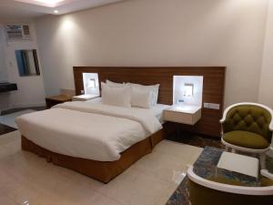 a bedroom with a large bed and a green chair at فندق تايا - Taya Hotel in Sūq al Aḩad