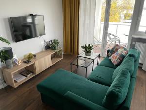 a living room with a green couch and a flat screen tv at Apartament RESORT Chełmońskiego Śrem in Śrem