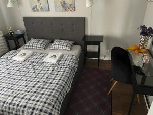 a bedroom with a bed with a plaid blanket and a desk at Apartament RESORT Chełmońskiego Śrem in Śrem
