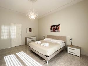 a white bedroom with a bed and a chandelier at Emma Home Matera in Matera
