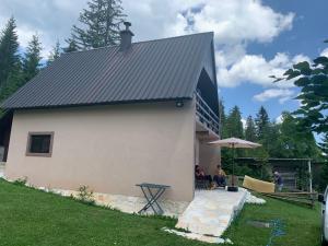 um edifício branco com um telhado preto com pessoas sentadas do lado de fora em Guest House Đina em Žabljak