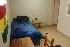 a small bedroom with a bed and a table at Expresso Hostel in Sucre