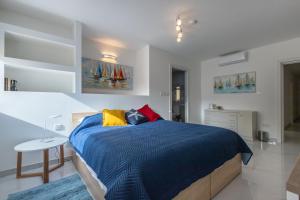 a bedroom with a blue bed with colorful pillows at Sliema Bedrooms with ensuite bathrooms in Sliema