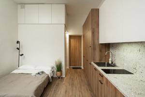 uma cozinha com um lavatório e uma cama num quarto em Air Apartment 102 em Vilnius