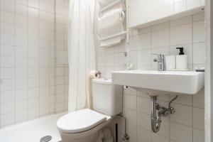biała łazienka z toaletą i umywalką w obiekcie Air Apartment 110 w Wilnie