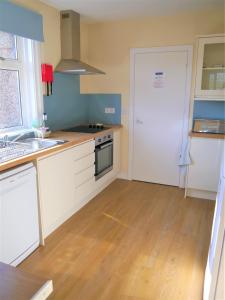 a kitchen with white cabinets and a sink and a door at Springfield in Dalbeattie
