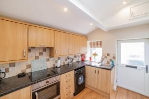 a kitchen with wooden cabinets and a washer and dryer at Jocks Hoose in Dumfries