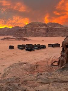 un grupo de bancos sentados en el desierto al atardecer en Bedouin host camp& with tour, en Wadi Rum