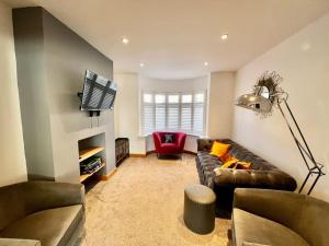 a living room with a leather couch and a tv at Stylish 3 bed house with Castle views in Lincolnshire