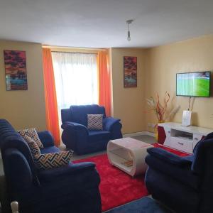 salon z niebieskimi krzesłami i telewizorem w obiekcie GCurtway Homes Nyayo 3 bedroom w mieście Nairobi