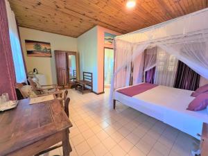ein Schlafzimmer mit einem Bett und einem Tisch in einem Zimmer in der Unterkunft Victory Hotel & Restaurant Tulear in Toliara