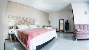 ジャグァルナにあるHospedaria das Pedras Sua Casa de Férias Litoral Santa Catarinaのベッドルーム1室(大型ベッド1台、ピンクの椅子付)