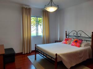 een slaapkamer met een bed met rode kussens en een raam bij Beach & Surf in Ribeira Grande