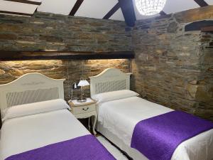2 camas en una habitación con una pared de piedra en Casas Rurales TAReira en Taramundi en Taramundi