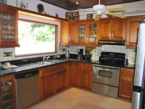 cocina con armarios de madera, fregadero y ventana en Splendide villa avec piscine à 200m de l'océan., en Parrita