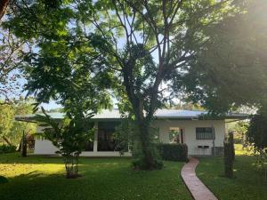 a white house with a tree in the yard at Splendide villa avec piscine à 200m de l'océan. in Parrita