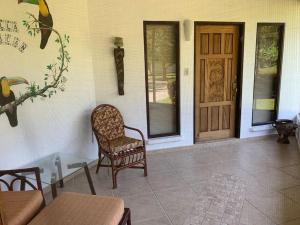 a porch with a chair and a wooden door at Splendide villa avec piscine à 200m de l'océan. in Parrita