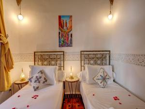 een kamer met 2 bedden en een schilderij aan de muur bij Palais Tinmel Marrakech in Marrakesh