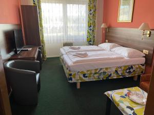 a hotel room with two beds and a television at Hotel Formanka in Hustopeče