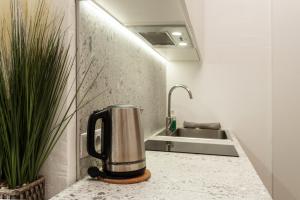 eine Kaffeekanne auf einer Theke neben einem Waschbecken in der Unterkunft Air Apartment 211 in Vilnius