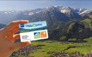 a person holding a credit card in front of a mountain at Ferienwohnung Lilli inklusive Bad Hindelang Plus in Bad Hindelang +5 photos