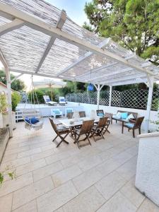 une terrasse avec une pergola blanche, une table et des chaises dans l'établissement VISTA MARE Su tre piani con giardino, à Falerna