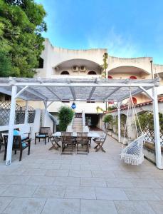 a patio with tables and chairs under a white pergola at VISTA MARE Su tre piani con giardino in Falerna +30 photos