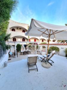 a patio with an umbrella and chairs in front of a building at VISTA MARE Su tre piani con giardino in Falerna