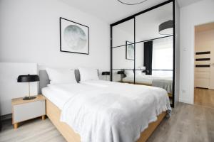 a bedroom with a large white bed and a mirror at Klif Apartamenty Nadmorskie Tarasy C403 in Kołobrzeg +22 photos