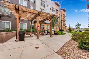 a wooden pergola with a picnic table on a sidewalk at Parks Residential Denver in Centennial