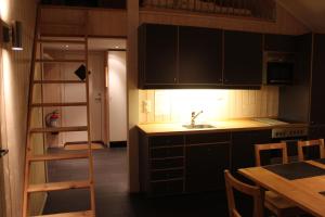 eine Küche mit schwarzen Schränken, einem Tisch und einer Leiter in der Unterkunft Gålå Fjellhytte - cabin with sauna and whirlpool tub in Sør-Fron