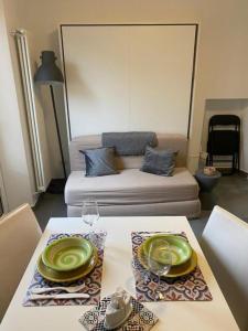 einen Tisch mit zwei grünen Tellern drauf mit einer Couch in der Unterkunft Alte Volat Casetta in Mailand