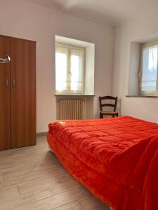 1 dormitorio con cama roja y armario de madera en Takápradalù, en Cisterna dʼAsti