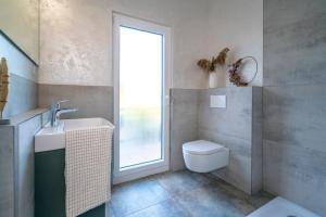 a bathroom with a toilet and a sink and a window at Feinheit Hotel & Restaurant in Halsenbach