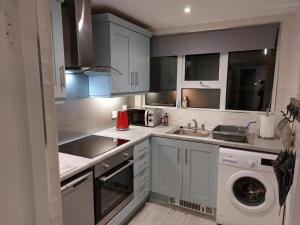 a kitchen with white cabinets and a washing machine at Jack's Place Beautiful 3-Bed House Donegal in Stranorlar