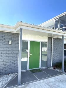eine grüne Tür auf einem Haus mit einem Gebäude in der Unterkunft Green Door - One bedroom apartment in Whakatane