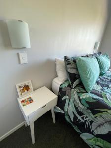 a bed and a nightstand next to a bed and a table at Green Door - One bedroom apartment in Whakatane +10 photos