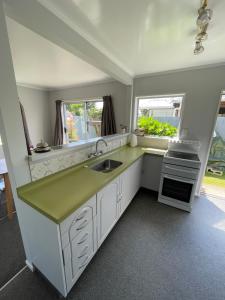 a kitchen with a sink and two windows at Green Door - One bedroom apartment in Whakatane