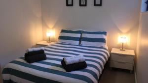 a bedroom with a blue and white striped bed with two lamps at Bluefish in Yamba