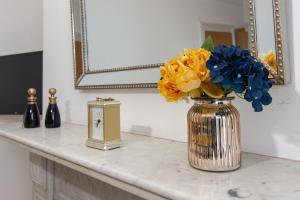 a vase of flowers sitting on a counter with a mirror at 147 The Residence, 5 bedrooms- Free parking in Belfast