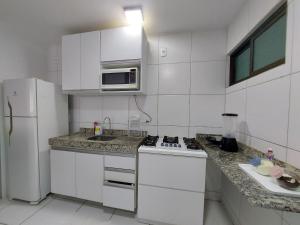 a white kitchen with a microwave and a refrigerator at Apartamento Encanto próximo ao Pátio do forró in Caruaru