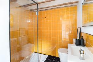 a yellow tiled bathroom with a toilet and a sink at Cosy cottage, walk to Porthcurno beach, Pedn Vouder, Minack & PK Museum in Penzance