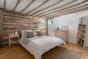 1 dormitorio con cama blanca y pared de madera en Cosy cottage, walk to Porthcurno beach, Pedn Vouder, Minack & PK Museum en Penzance