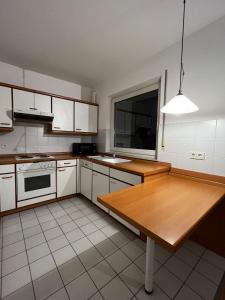 a kitchen with white cabinets and a wooden table at Komplette Wohnung 40m2 mit schöner Terrasse Niedernhausen in Niedernhausen