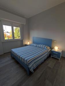 a bedroom with a bed with two night stands and two windows at Casa Violina in Lido di Camaiore