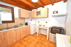 a kitchen with wooden cabinets and a white refrigerator at Ninas Cottage in Línia