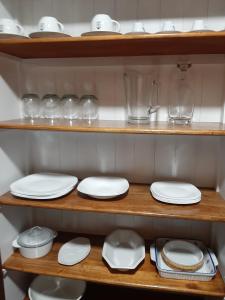 un estante con platos blancos y gafas. en Casa excelente ubicación en Mendoza