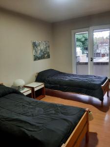 a bedroom with two beds and a window with a patio at Casa excelente ubicación in Mendoza